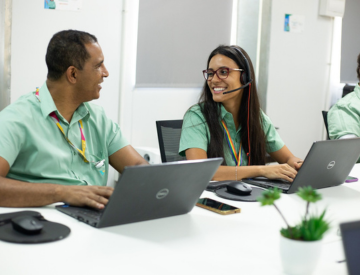 A man and a woman smiling looking at each other in front of notebooks.