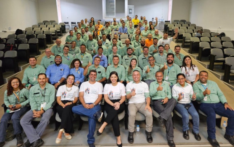 Várias pessoas em uma auditório olhando para uma foto