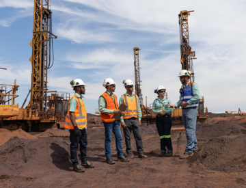 A group of Vale's employees wearing safety uniforms and talking in a construction place.