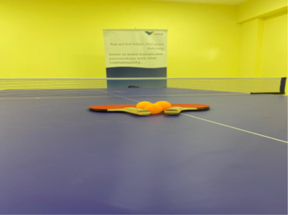Image of a tennis table with two rackets and some balls on top of it.