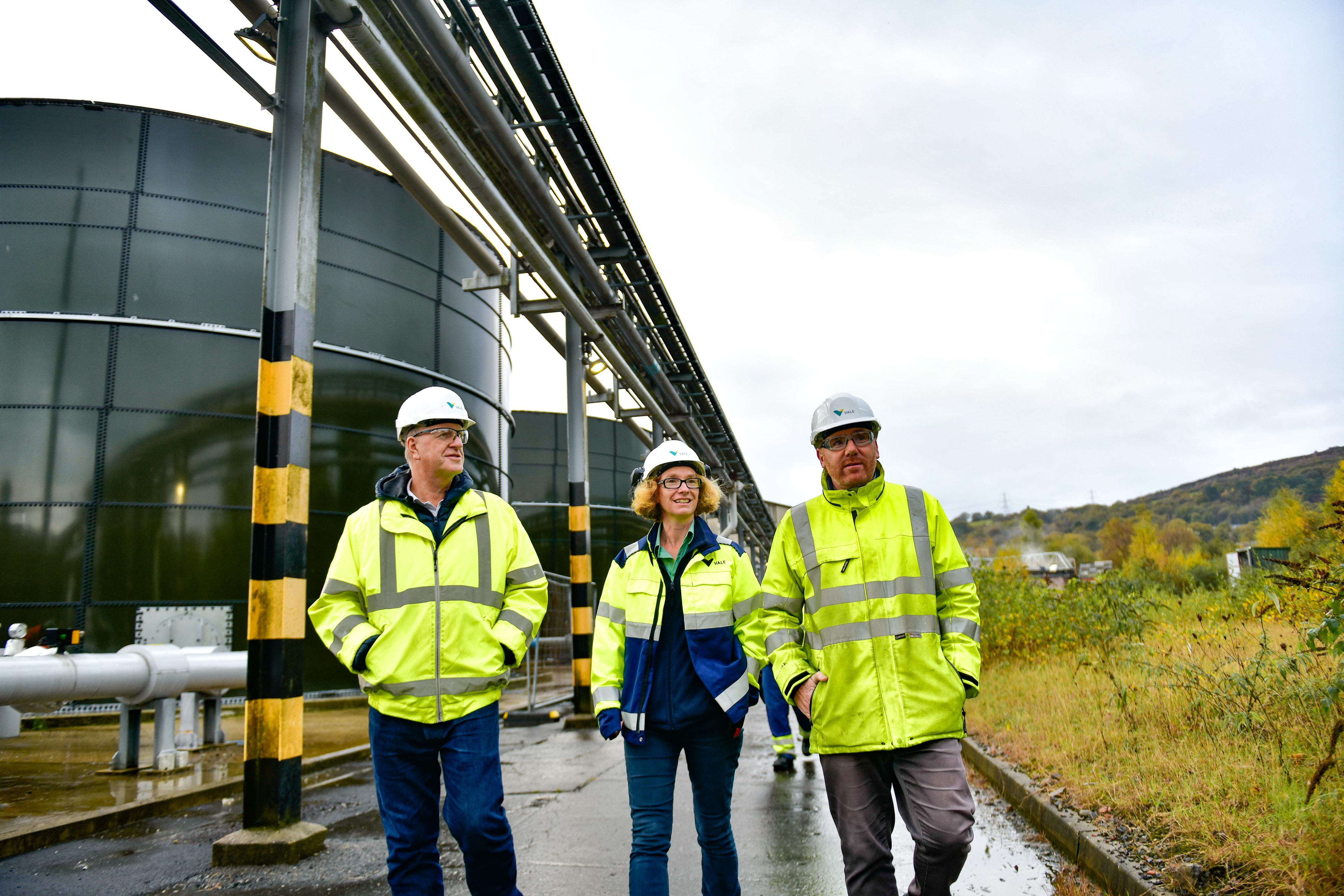 Three employees, two man and one women, are walking in an operations areas