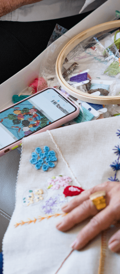 Photo of a hand under fabric embroidered with colored threads.