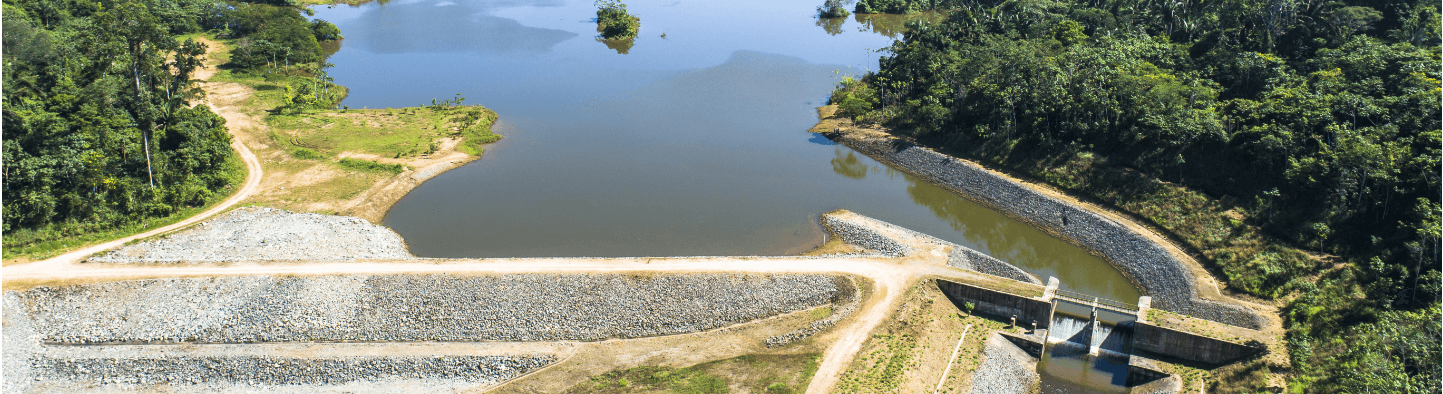 Foto de barragem eliminada com pedras, um rio, caminho de terra e vegetação ao redor