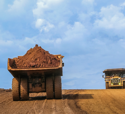 On a dirt road, a truck loads sediment