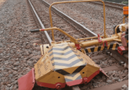 Photo of the device on top of track ballast, cleaning it