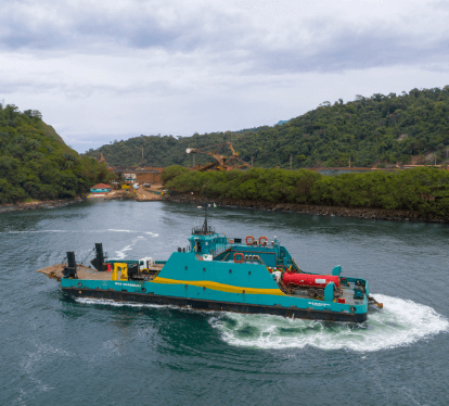 Barco operacional verde e amarelo flutuando em um grande lago.