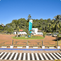 Foto de uma parte da Fazenda Marinha com uma sinalização no chão com listras preta e branca, um gramado em formato circular com uma placa com o logo da Vale e ao fundo uma casa e uma vegetação.