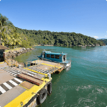 Photo of a port with a ramp structure, signaling, buoy, sea, vegetation and a boat nearby.