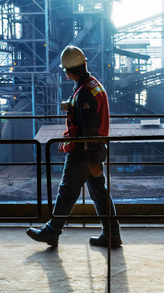 Uniformed employee with safety equipment walks in work site.