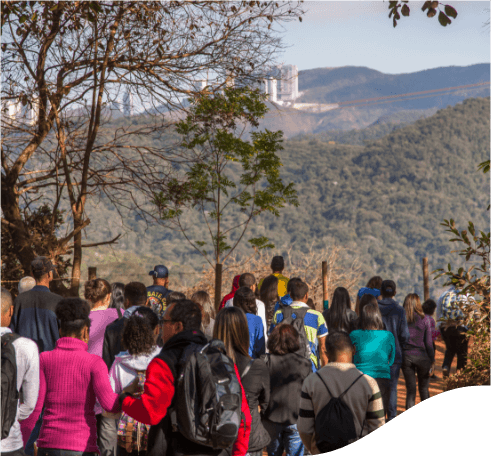 Várias pessoas caminhando umas atrás das outras em uma região arborizadas.