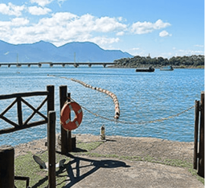 Photo of a sea and concrete part with railing and a hanging lifebuoy