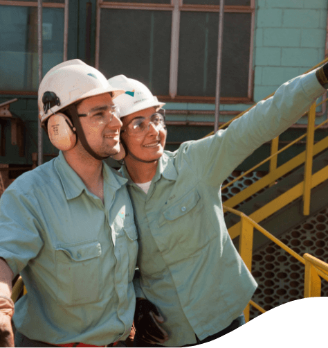 Empregados vale, trajados com o capacete de segurança, olhando para o alto.