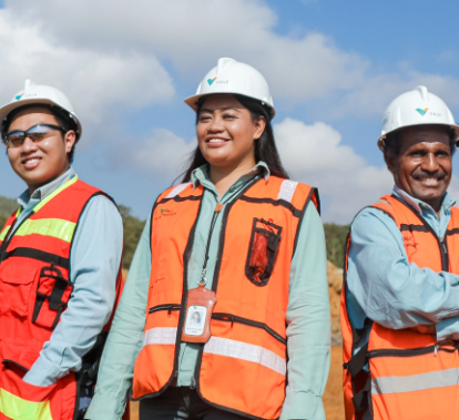 A group of Vale employees in an open area. They are wearing vests, uniforms and protective hats.