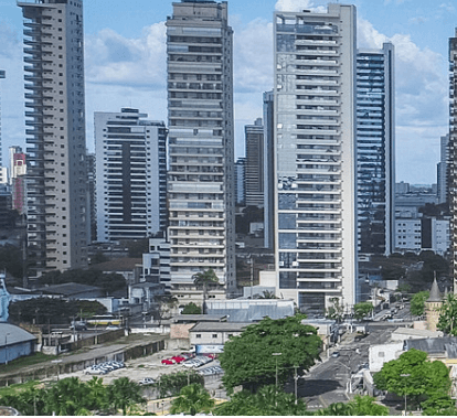 Foto de uma cidade com vários prédios altos, ruas e alguns guindastes próximo à um galpão.