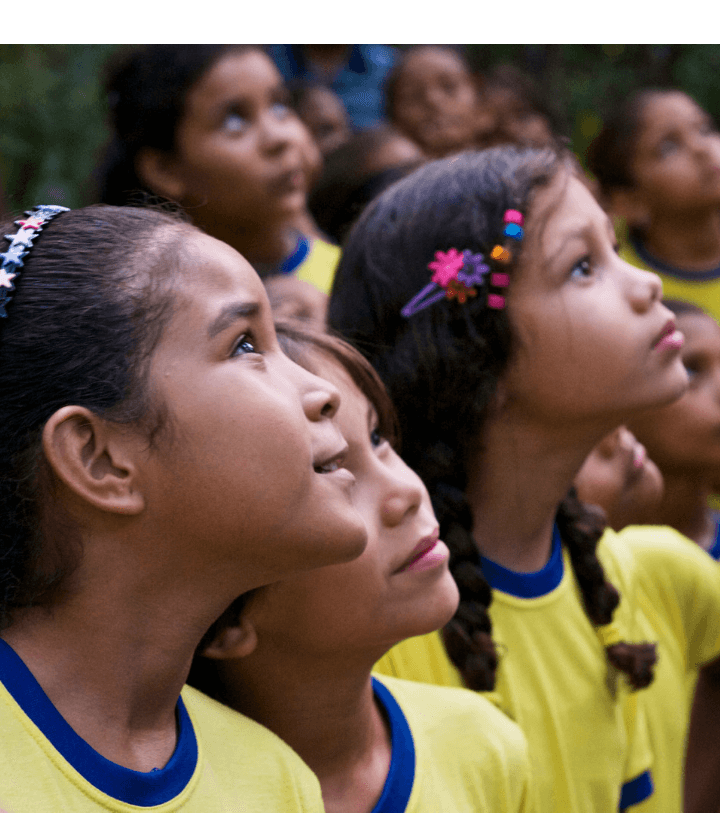 Several children look up with attention. They all wear yellow school uniforms with dark blue collars.