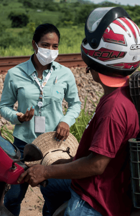Uma empregada Vale conversa com um motoqueiro. Os dois estão próximos de uma ferrovia.
