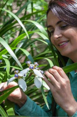 A Vale female employee is holding an orchid and smiling.