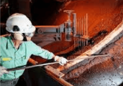 Photo of an employee wearing Vale uniform and hard hat with device in hand, in pellet plant