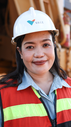 Seorang karyawan yang mengenakan helm dan rompi reflektif tersenyum simpatik saat difoto.