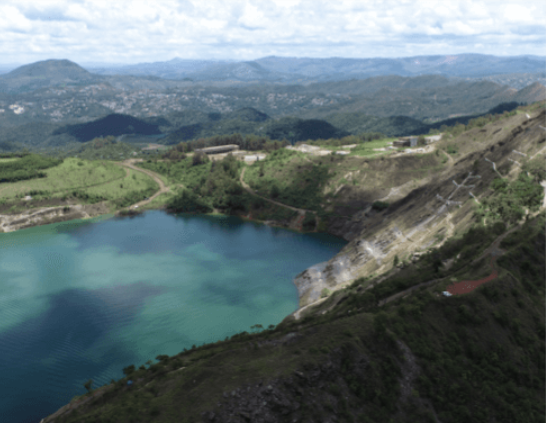 Foto de várias montanhas cobertas por vegetação verde e no meio mais para esquerda um grande lago de água na cor azul clara e escura