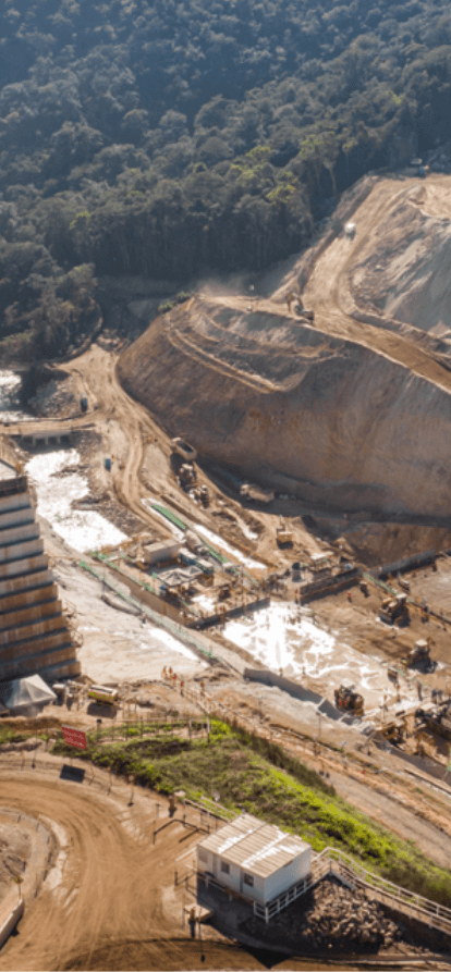 Estrutura de contenção em obra com terra, concreto e vegetação ao redor.