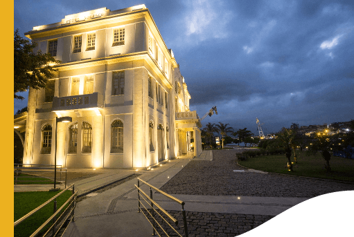 Night shot of the side entrance of the Vale Museum. The place is a large building with old architecture and has lights illuminating the beige facade.