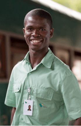 A Vale employee. He is black, smiling, has short hair, and wears the green uniform with the hanging badge.