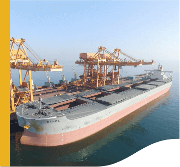 Large cargo ship docked at the Sohar port. Next to it are about three pieces of crane-like equipment