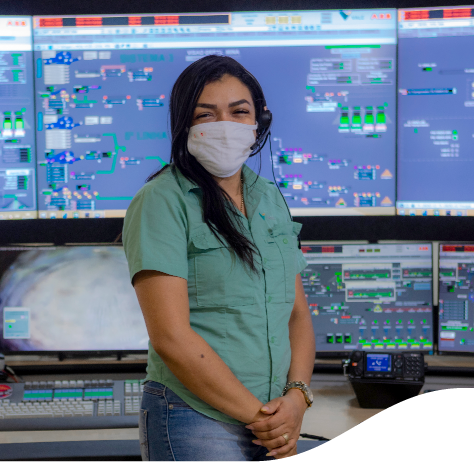 Vale employee, standing in a room full of monitors. She is wearing a mask and a headset.