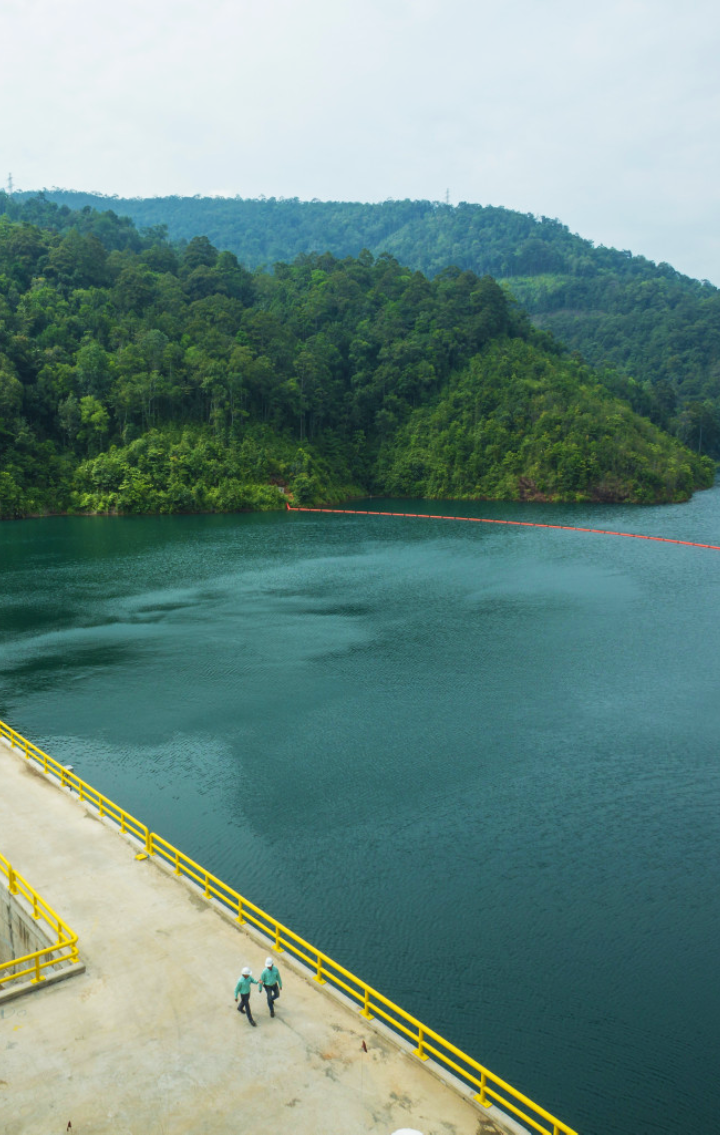 Two employees walk on a bridge over a river.