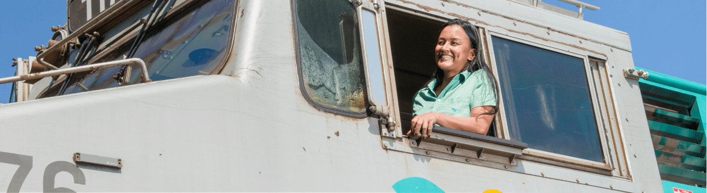 A woman smiling in the direction of one of Vale's trains. She is wearing a light green shirt.