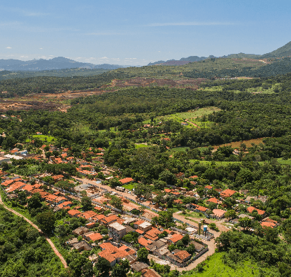 Foto de uma cidade vista de cima com bastante vegetação e algumas casas.