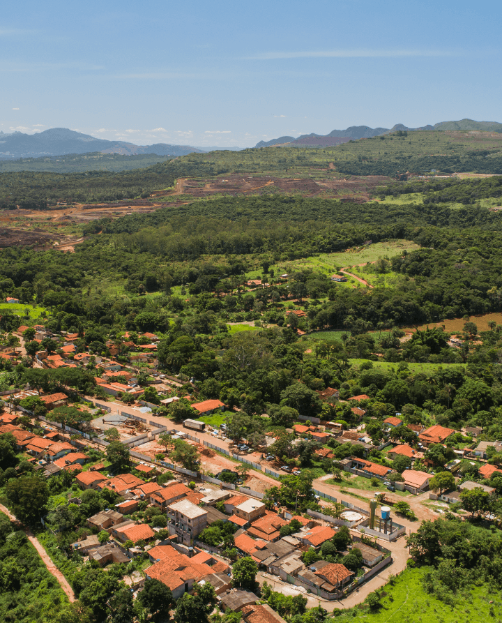 Foto de uma cidade vista de cima com bastante vegetação e algumas casas.