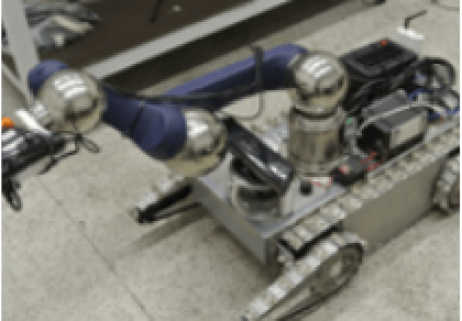 Photo of equipment, showing wheels, robotic arm and other parts