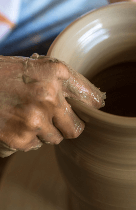 Uma mão moldando um vaso de cerâmica.