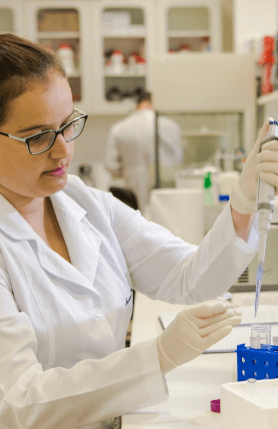 A scientist, in a white lab coat and gloves, handling a test tube in a laboratory.