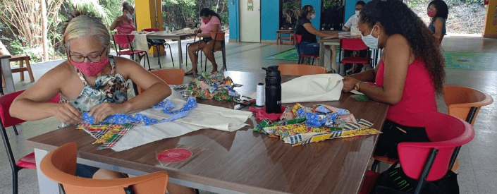 Several women are seated around tables, handling fabrics.