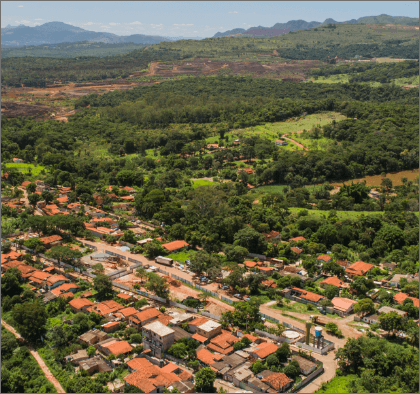 Aerial image of a city. The place is surrounded by vegetation and there are many houses in the center.
