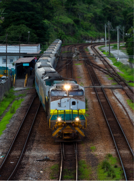 Duas imagens retangulares separadas por um pequeno espaço em branco. A primeira é uma imagem aérea de um trem da Vale trocando de trilho. A segunda é uma foto de frente da primeira cabine do trem de carga da Vale.