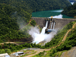 Foto da pequena central hidrelétrica Wabageshik com uma estrutura de concreto, pedras, vegetação e água em movimento passando pelas estruturas.