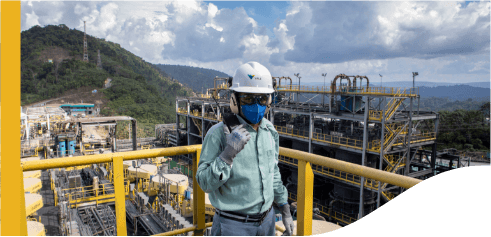 A Vale employee is in an outdoor operating area. He is wearing various protective equipment and a radio transmitter.