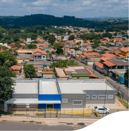 Foto aérea de uma unidade da saúde apoiada pela Vale, cercada por diversas casas da cidade e árvores. A unidade de saúde é pintada nas cores cinza e azul.