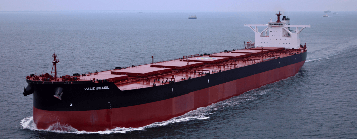 Image of a large cargo ship. It is red and has a black stripe, and is sailing on the high seas.