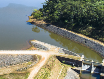 Foto de barragem eliminada com pedras, um rio, caminho de terra e vegetação ao redor