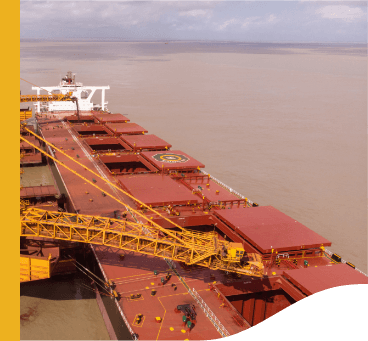 Image of the top of a large cargo ship, with yellow equipment operating. In the background the waters are murky.
