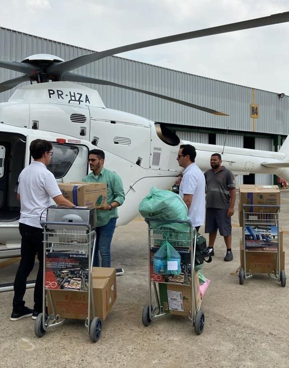 Homens carregam caixas com doação próximo a helicóptero